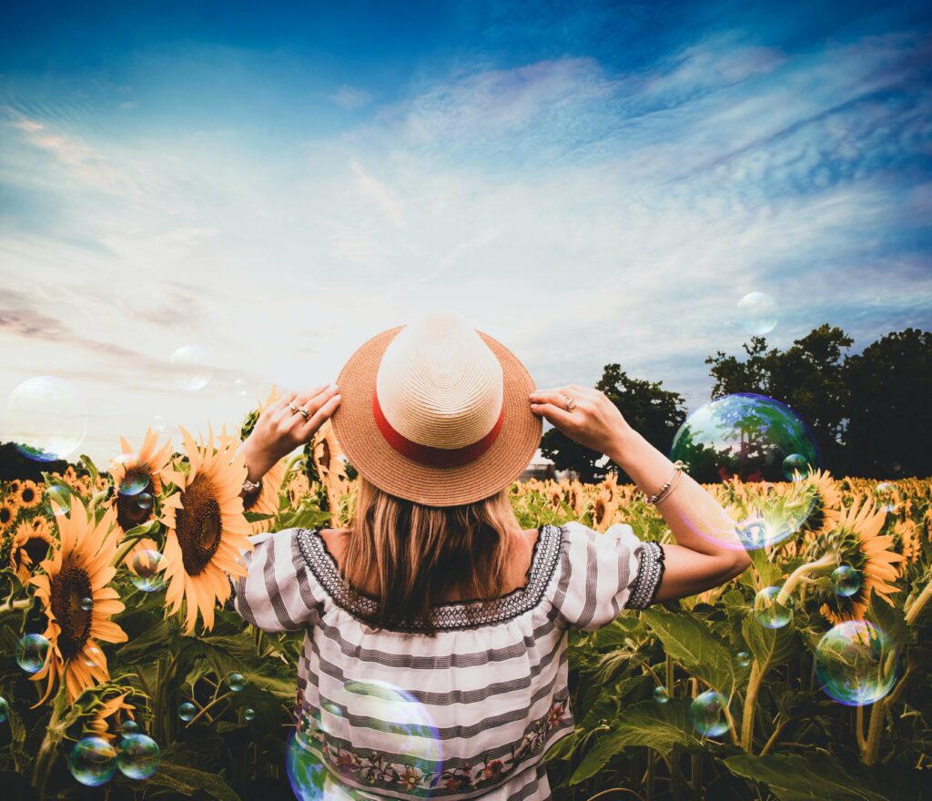 woman wearing hat looking at field of sunflowers
